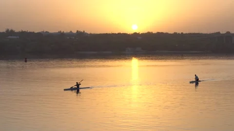 Two guys kayak in the evening at sunset on the river water in which shimmers Stock Footage 138569384