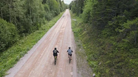 Two guys mountain biking along a gravel road in the mountains Stock Footage 145870137