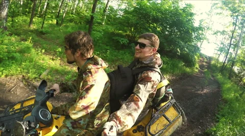 Two guys on quad ride through the forest Stock Footage 57699535