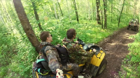 Two guys on quad ride through the forest Stock Footage 57699739
