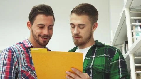 Two guys read papers in a folder and laugh Stock Photos