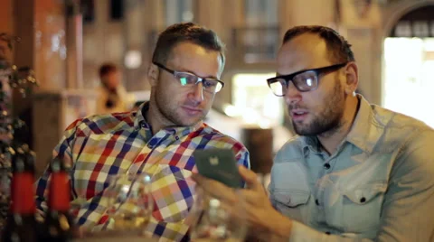 Two guys with smartphone talking in the restaurant at night, steadycam shot 스톡 동영상 36630694