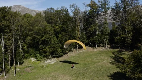 Two guys taking of from the green hill with tandem paraglide on a sunny day Stock Footage 120116817