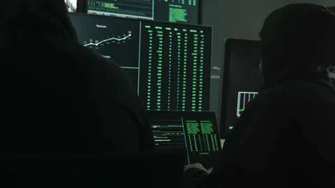 Two hackers coding to hack company servers, using monitor screens with green Stockbeeldmateriaal 228197523