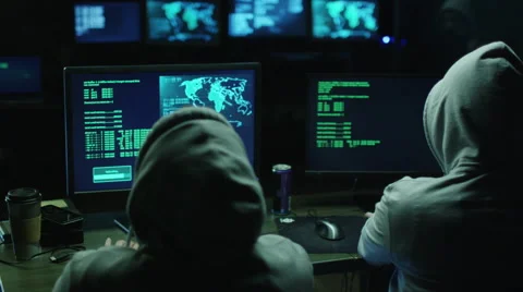 Two hackers in hoods work on a computers with maps and data on display screens Stock Footage 59153200