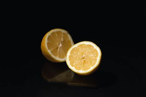 Two half of lemon fruit on black background with reflection. Stock Photos