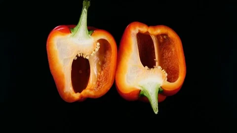 Two half of red bell pepper rotate in front of black background. 4K 스톡 동영상 74060374