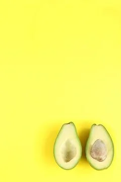 Two halfs of avocado with and without seed on yellow background. Stock Photos
