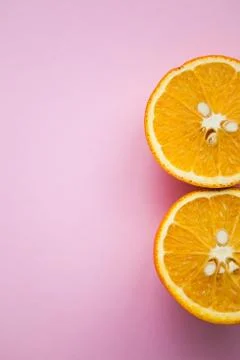 Two halfs of oranges on pink background with copy space Stock Photos