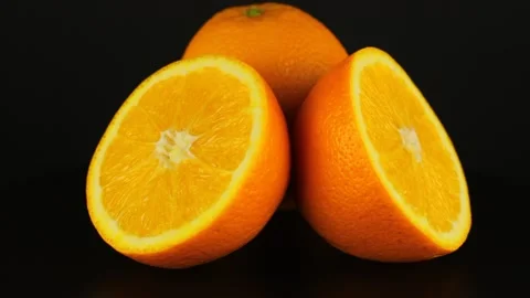 Two halves and one whole oranges rotates on a black background. 스톡 동영상 151538899