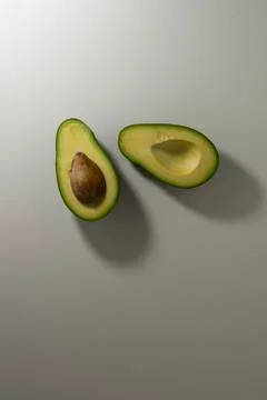 Two halves of avocado fruit with kernel on a light background. top view Stock Photos