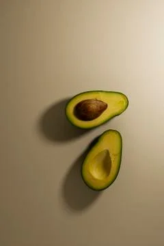 Two halves of avocado fruit with kernel on a light background. top view Stock Photos