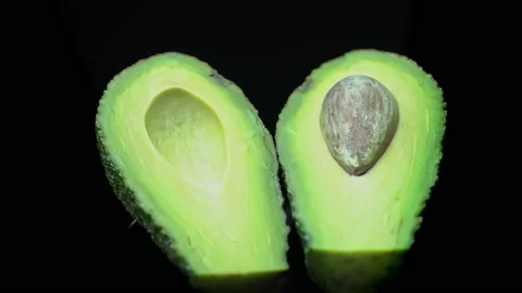 Two Halves of an Avocado Rotate in a Circle on a Black Background Stock Footage 172635665