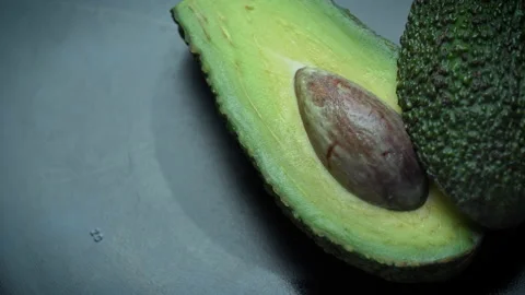 Two Halves of an Avocado Rotate in a Circle on a Black Background Video stock 173121851