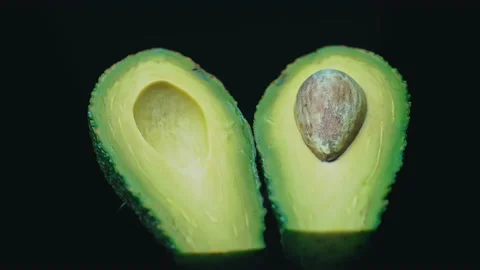 Two Halves of an Avocado Rotate in a Circle on a Black Background Stock Footage 174670745