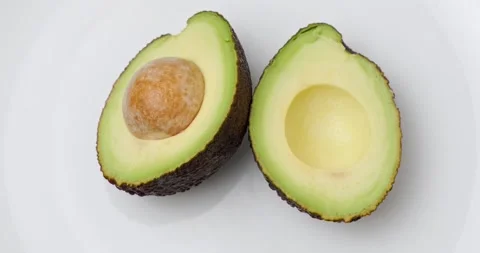 Two halves of avocado with a stone Stock Footage 227041296