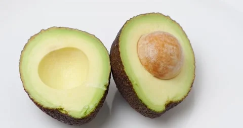 Two halves of avocado with a stone Stock Footage 227041656