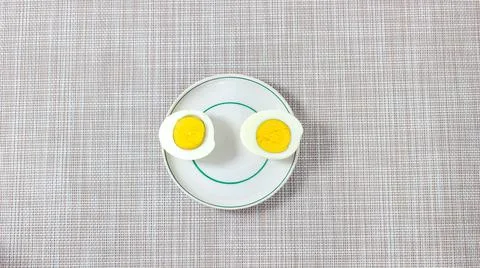Two halves of a boiled egg on a plate in the form of eyes. Stock Photos
