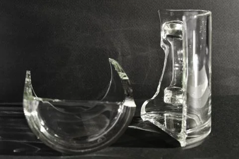 Two halves of a broken cup stand on a black background. Broken. Stock Photos