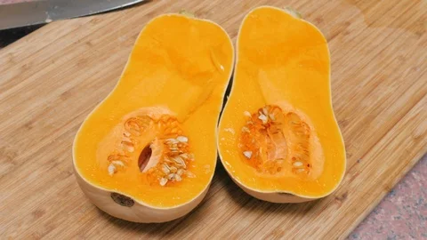 Two Halves of a Butternut Squash Rest on a Wooden Cutting Board in 4k Stock Footage 86254974