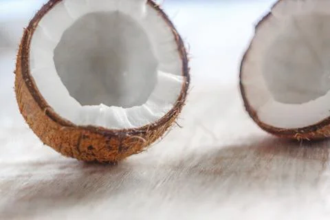 Two halves of coconut on a light white wooden background, close-up. View from Stock Photos
