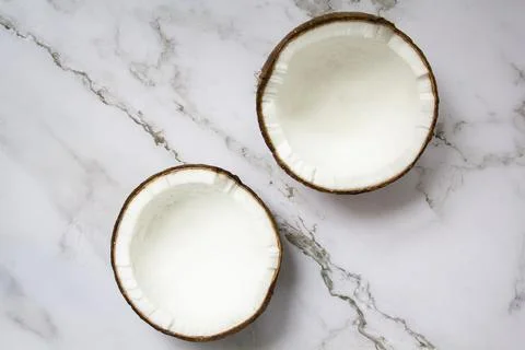 Two halves of coconut on marble background. Top view Stock Photos
