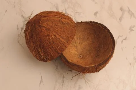 Two halves of a coconut shell on a marble background, isolate. Stock Photos