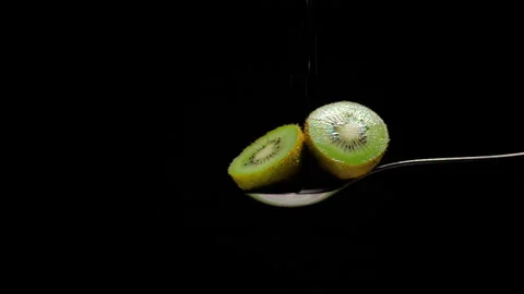Two halves of cut kiwi falling slow motion white sugar Stock Footage 131406252