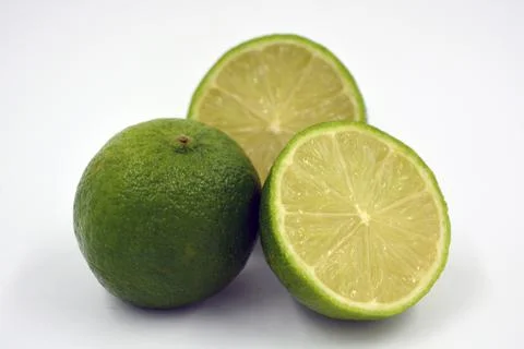 Two halves of a cut lime and a whole lime on a white background. Foto stock