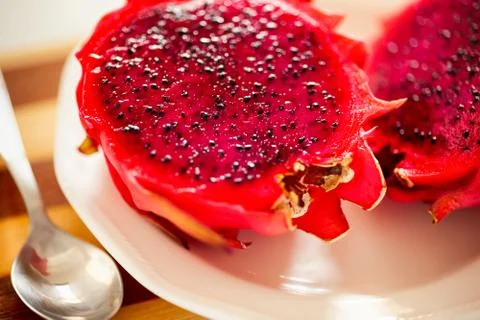 Two halves of Dragon fruit on white plate with spoon. Stock Photos