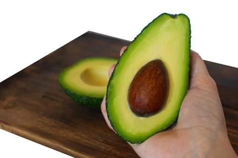 Two halves of green avocado in the hands of a woman Stock Photos
