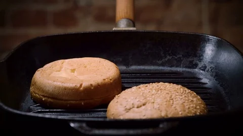 Two halves of hamburger bun are being fried in a broiler pan for burger. 4K Stock Footage 82359426
