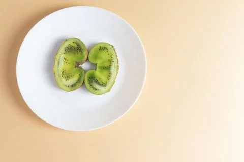 Two halves of kiwi, on a peach background a sweet ugly fruit.. Stock Photos