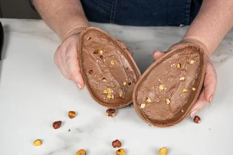 Two halves of a milk chocolate Easter egg filled with hazelnut cream. Stock Photos