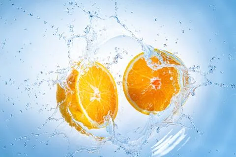 Two halves of orange fruit splashing into clear water. Stock-Fotos