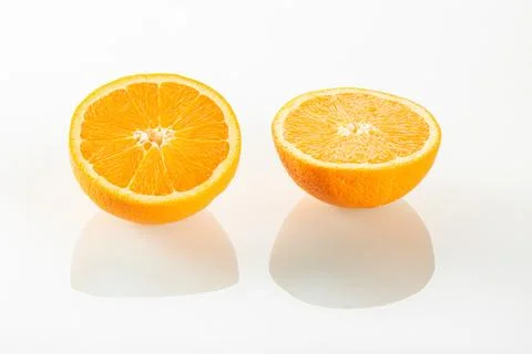 Two halves of an orange with reflection on a white mirror background Stock Photos