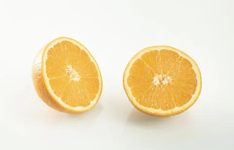 Two halves of an orange with reflection on a white mirror background Stock Photos
