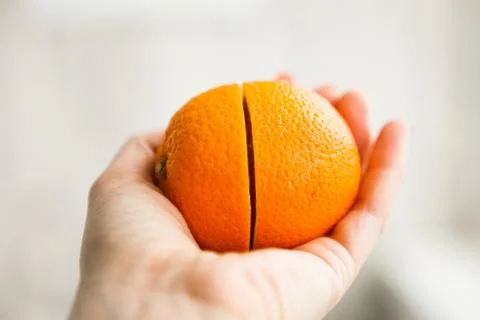 Two halves of orange in somebody's hand Stock Photos