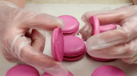 Two halves of pink Macaroon in the hands of chief Stock Footage 62426091