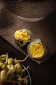 Two halves of quail eggs on cloth and wooden board next to mung beans Stock Photos