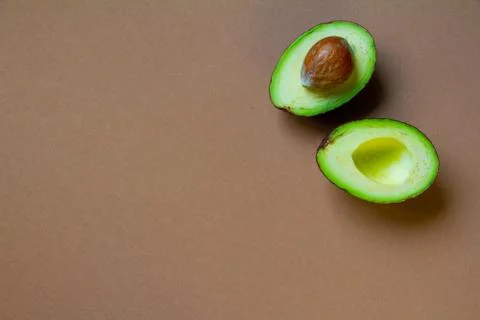Two halves of raw avocado on brown background, creative food concept Foto stock