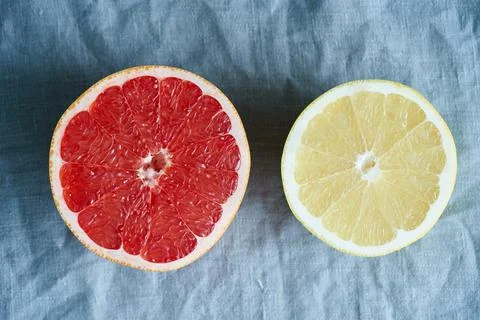Two halves of red and white grapefruit, bright circles on a dark gray linen Foto stock