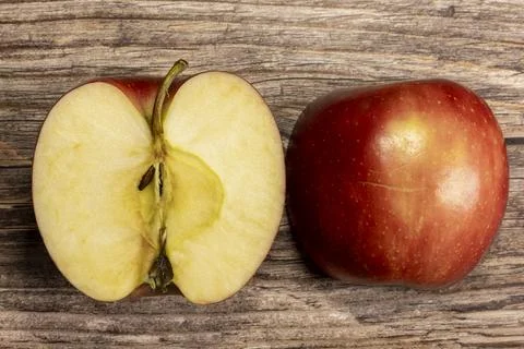Two halves of a red apple on a rustic wooden table from above Stock Photos