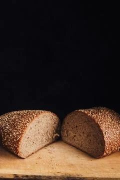 Two halves of sliced bread sprinkled with sesame seeds on a wooden cutting .. 库存照片
