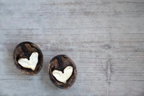 Two halves of split walnut with core in form of white hearts on wooden Stock Photos