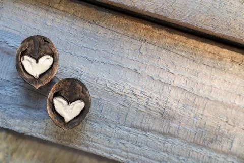 Two halves of split walnut with core in form of white hearts on wooden Stock Photos