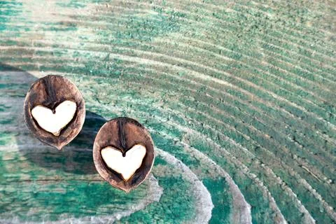 Two halves of split walnut with core in form of white hearts on wooden Stock Photos
