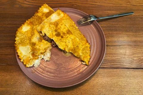 Two halves of torn cheburek on pink plate, top view Stock Photos