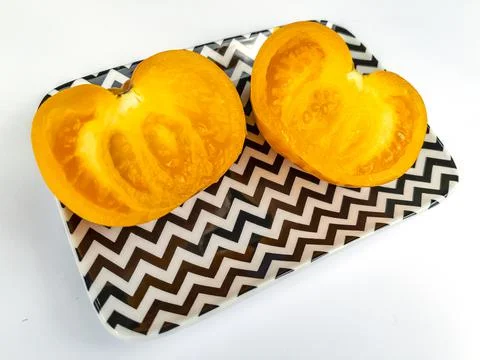 Two halves of a yellow tomato on a rectangular plate Stock Photos