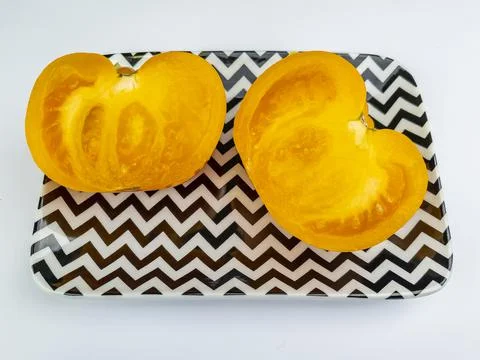 Two halves of a yellow tomato on a rectangular plate Stock Photos